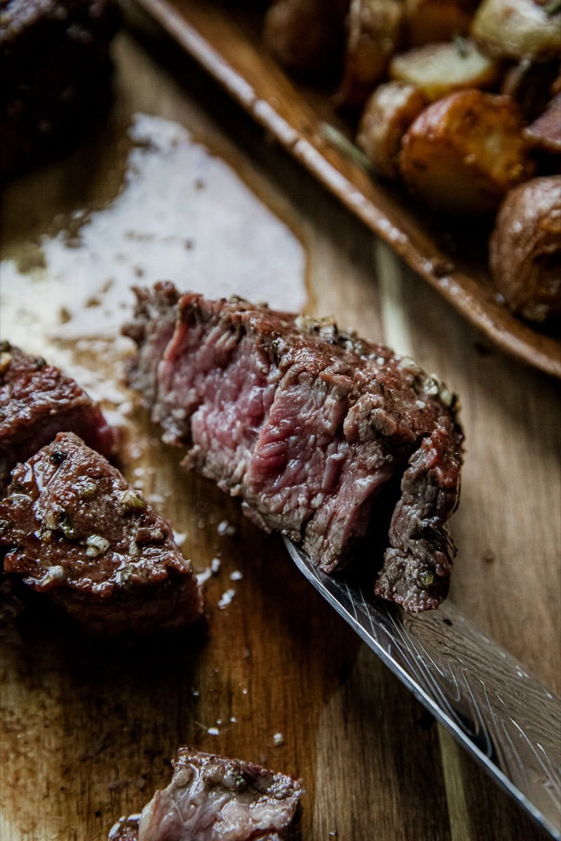 Juicy grilled skirt steak with chimichurri sauce on a wooden cutting board.