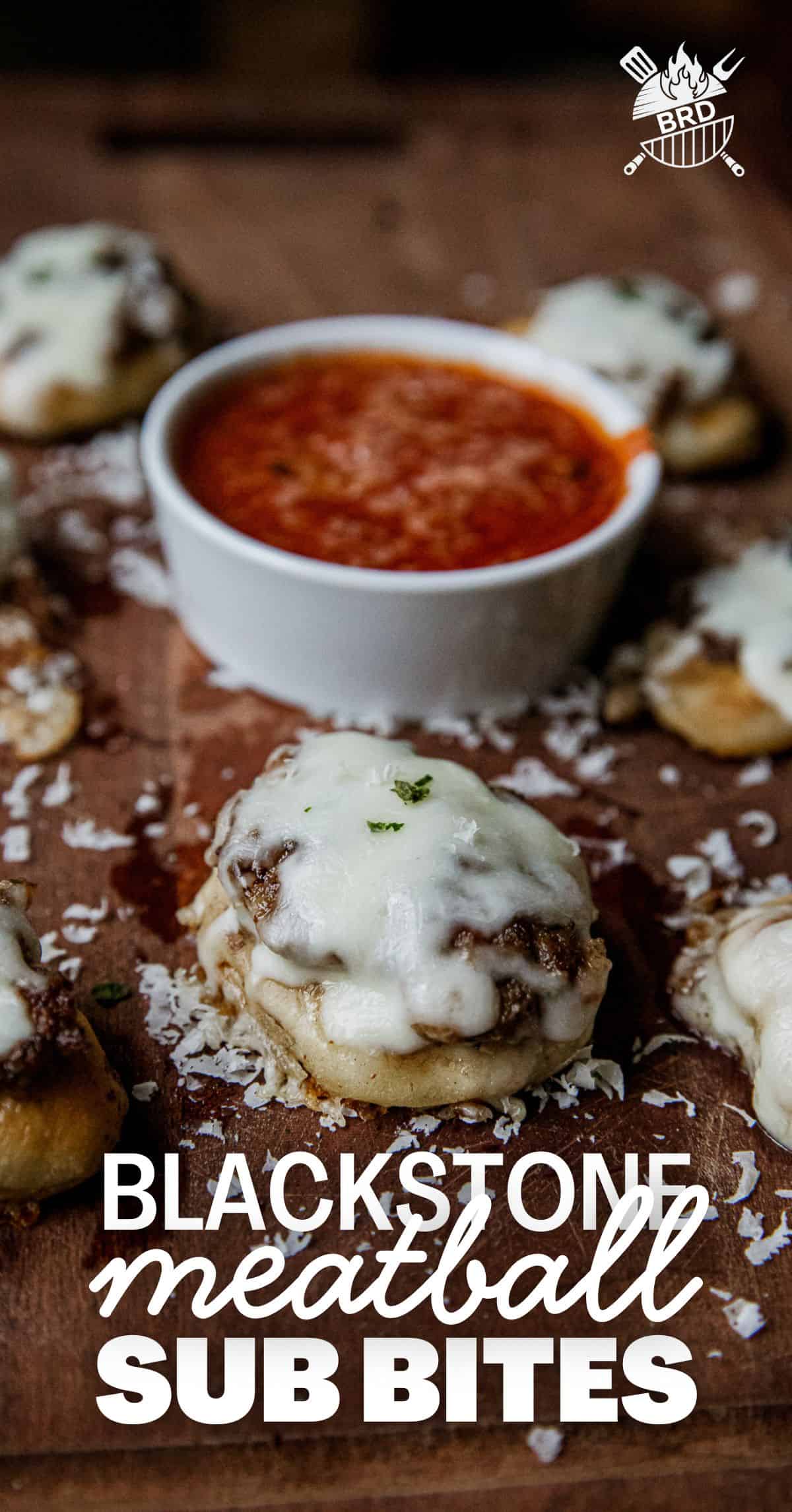 Delicious mini meatball sub bites with melted cheese and herbs on a wooden surface.